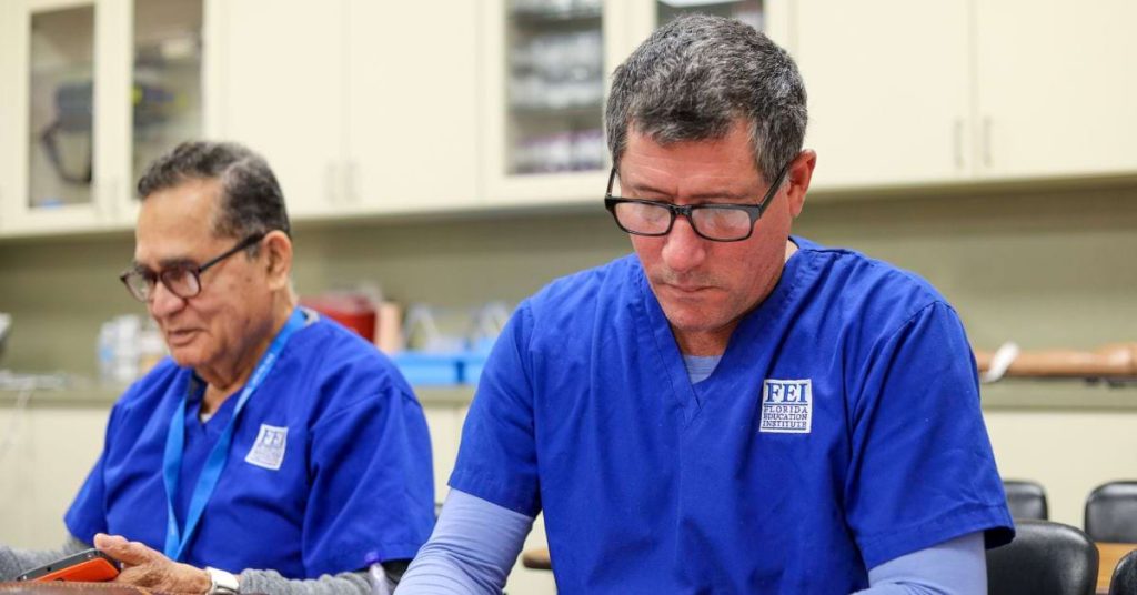 Image of two students wearing blue Florida Education Institute scrubs in a classroom